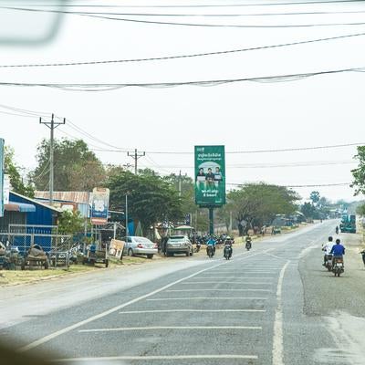 カンボジアの国道沿いに広がる商店街と電線が張り巡らされた街並みの写真