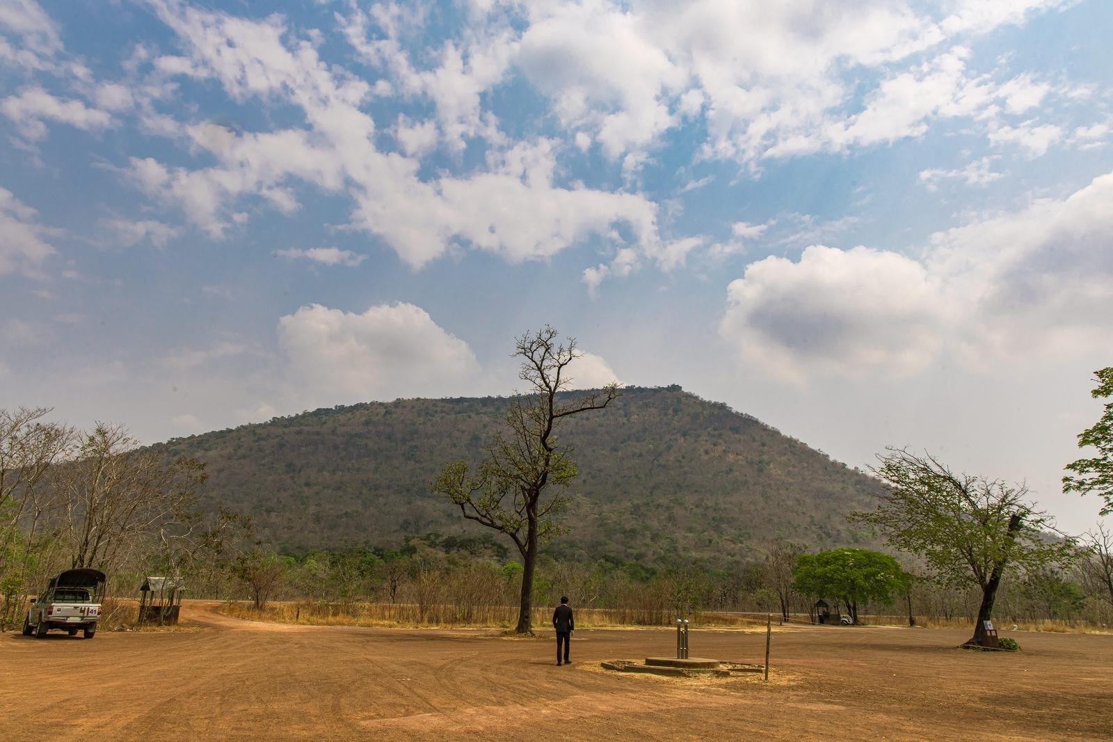 「プレアヴィヒア寺院がある山を目の前にするスーツ姿の男性」の写真［モデル：野崎繁裕］