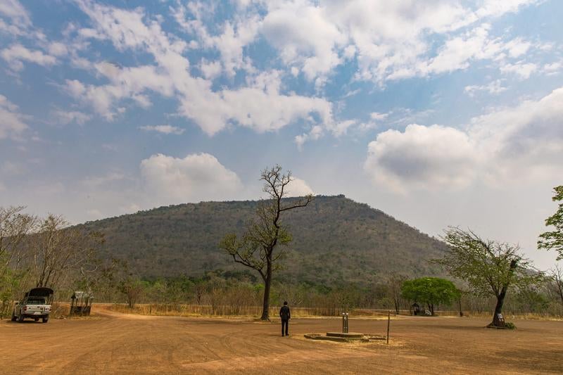 プレアヴィヒア寺院がある山を目の前にするスーツ姿の男性の写真