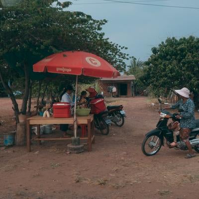 赤いパラソルの屋台と地元住民のスクーターの写真
