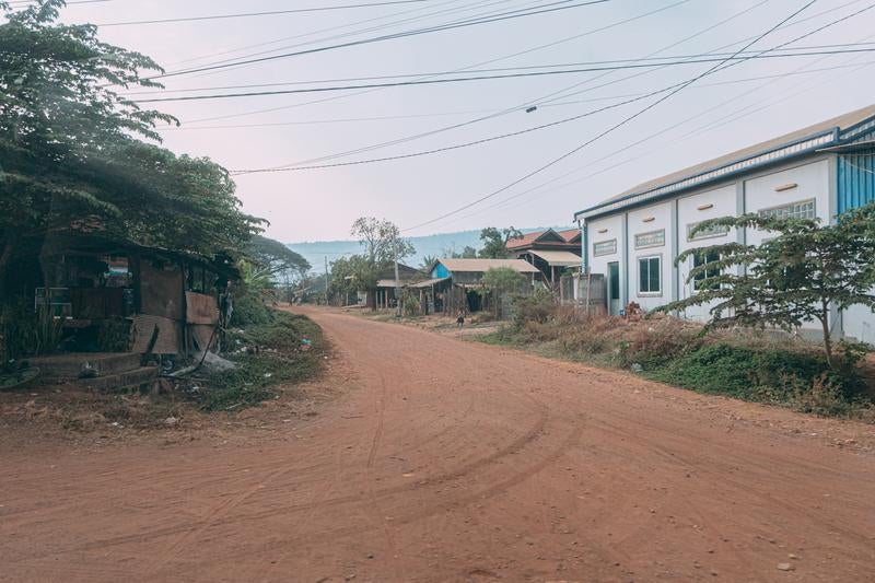 Unpaved Red Dirt Road and Houses in a Cambodian Countryside Town