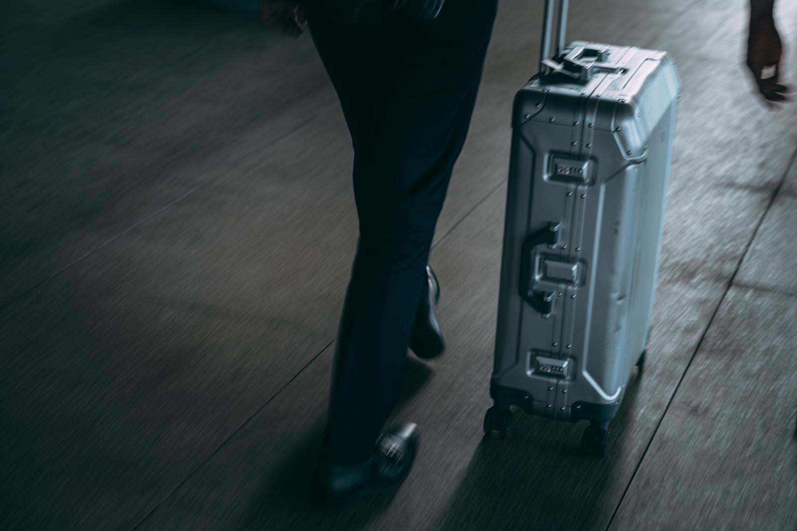 「空港で荷物を運ぶ旅行者の様子」の写真