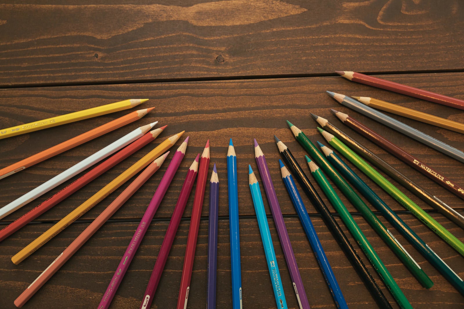 「木目のテーブルとカラフル色鉛筆」の写真