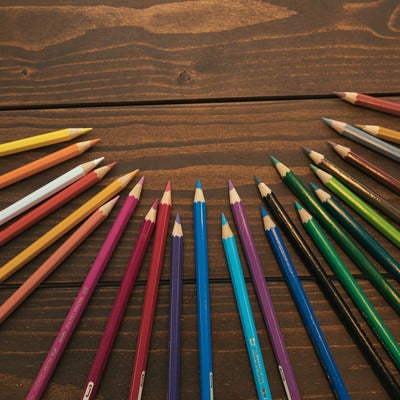 木目のテーブルとカラフル色鉛筆の写真