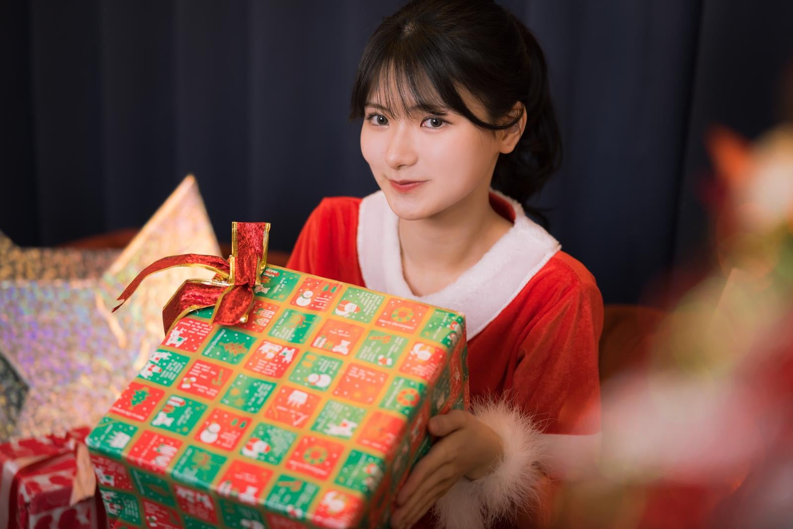 「クリスマスにプレゼントを手渡しする女性サンタ」の写真［モデル：モデルリリース］