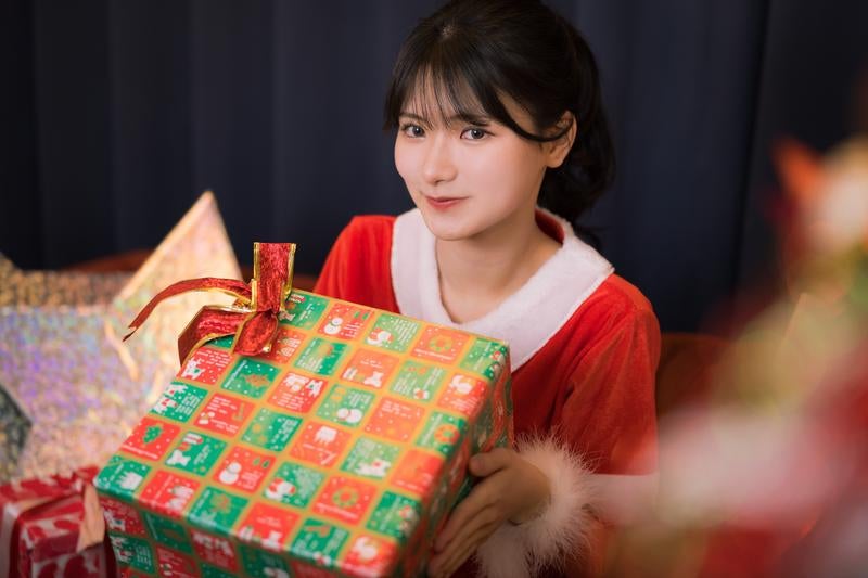 クリスマスにプレゼントを手渡しする女性サンタの写真