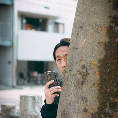 木陰に隠れながらスマホで盗撮する男性（41歳）の写真