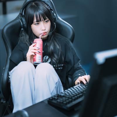 エナドリを飲みながらゲーミングチェアで休憩中のゲーマー女子の写真