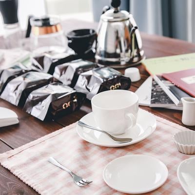 木製テーブルに置かれた白いコーヒーカップとティーポットの写真