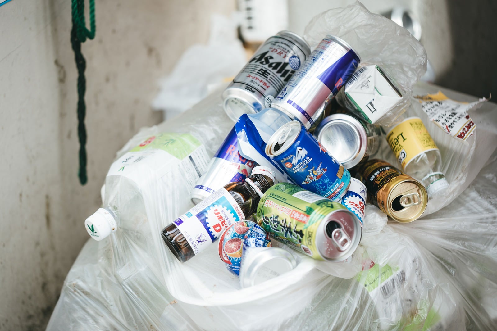 「ゴミ袋がある場所に捨てられていく空き缶の山」の写真