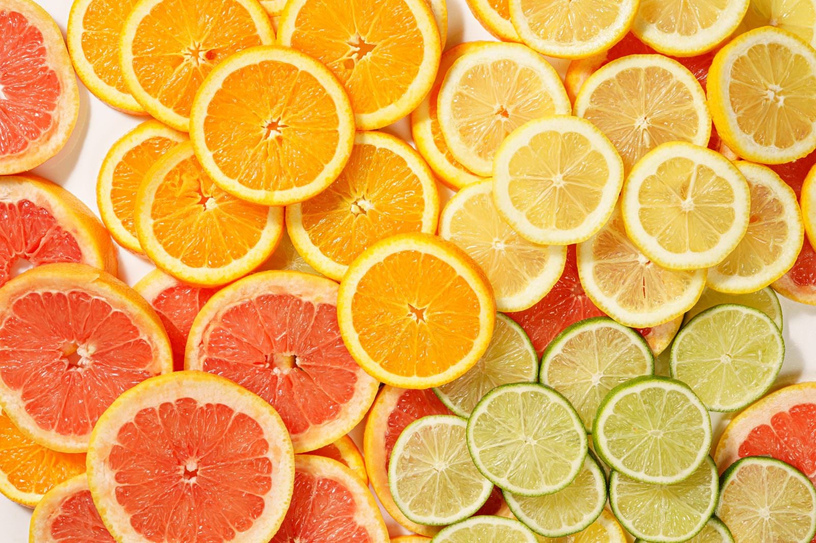 「カットされて並んだグレープフルーツやライムなどの柑橘類」の写真