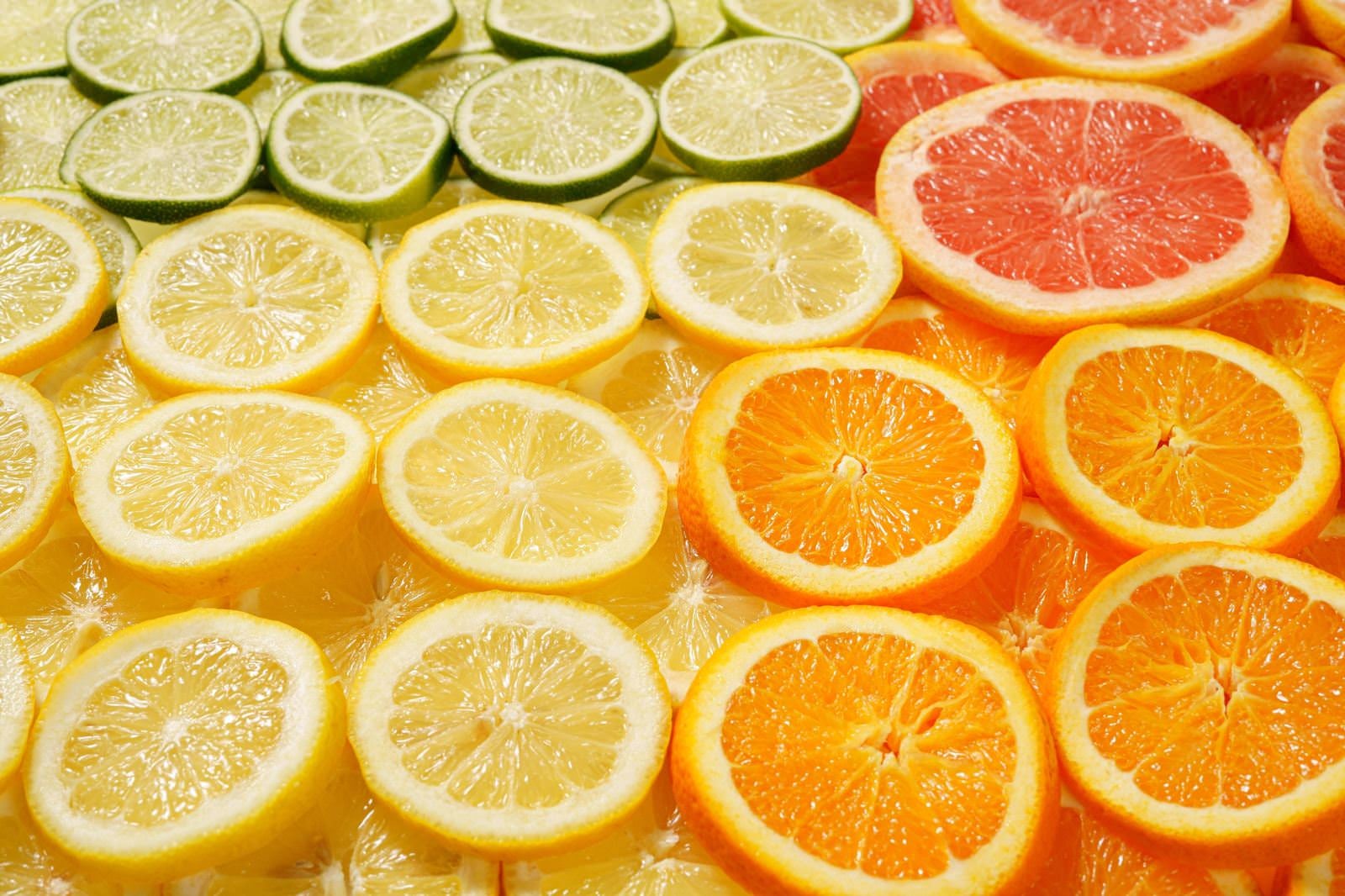 「輪切りして並んだグレープフルーツやオレンジなどの果物」の写真