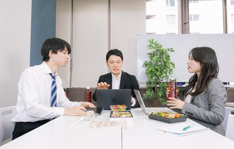 昼食を取りながら会議するビジネスマンたちの写真