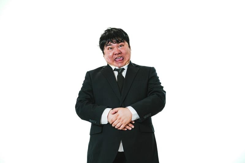 黒いスーツを着た男性が驚いた表情で腕組みの写真