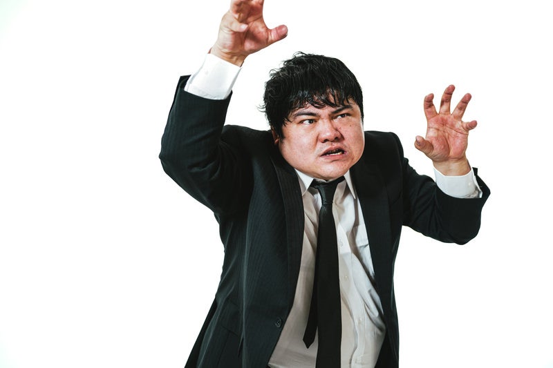 両手を使って威嚇する男性会社員の写真