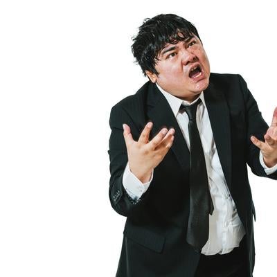 両手を広げて激怒するスーツ姿の会社員の写真