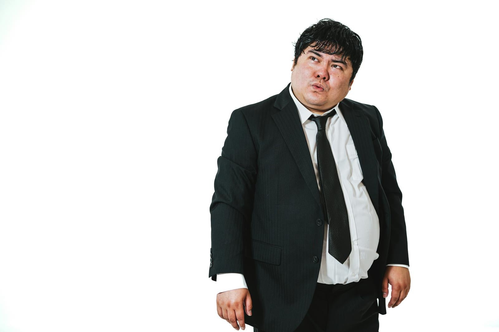 Stout businessman in suit on white background puckering lips and glancing upward while gauging the situation