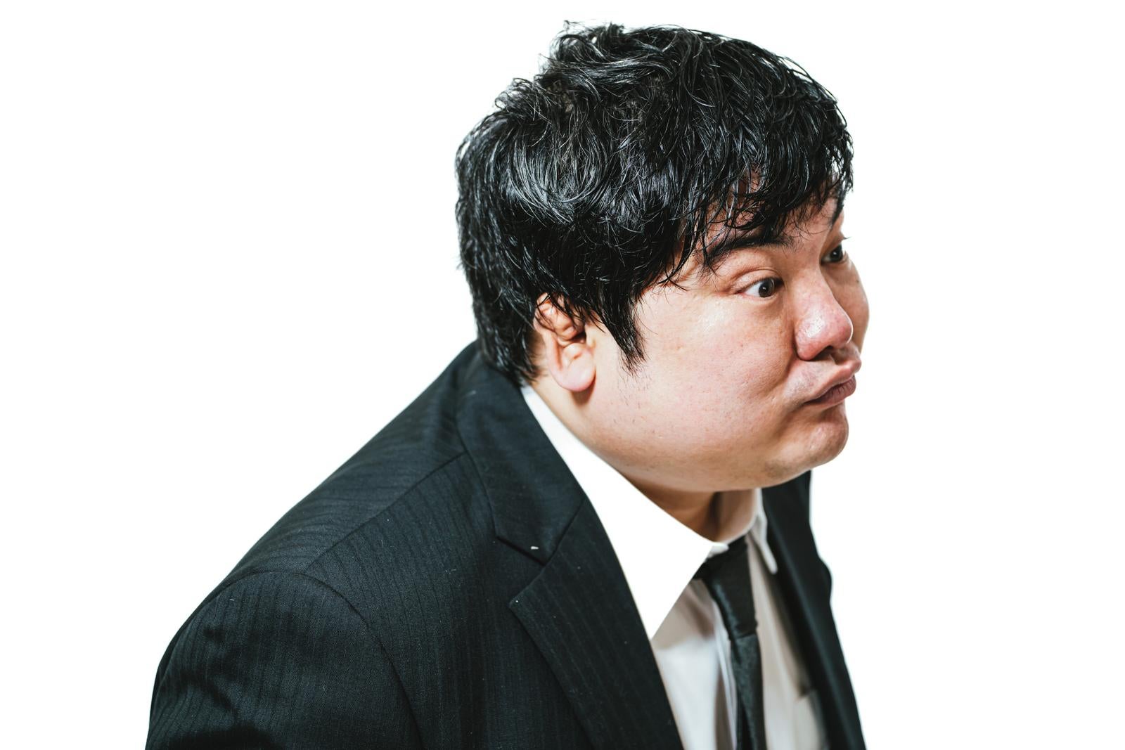 紺色のストライプスーツを着た男性が斜め後ろ向きで立つ横顔写真［モデル：段田隼人］