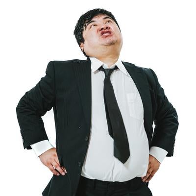 腰に手を当てて威張るスーツの男性の写真