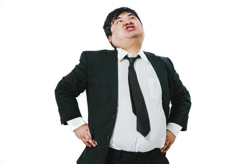 腰に手を当てて威張るスーツの男性の写真