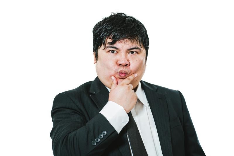 顎に手を当てて考え込むスーツ姿の男性の写真