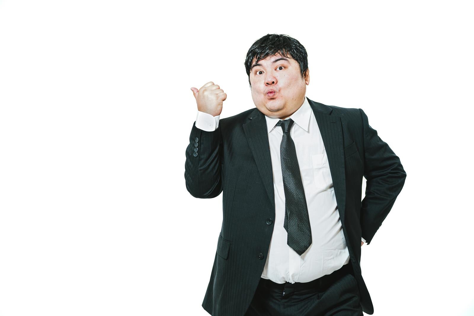 スーツ姿の男性が左手をこぶしにして握りしめ、口を開けてポーズを取っている［モデル：段田隼人］