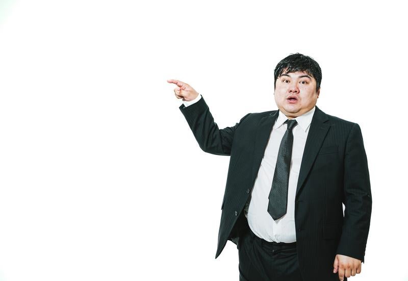 左方向を指さすスーツ姿の男性の写真