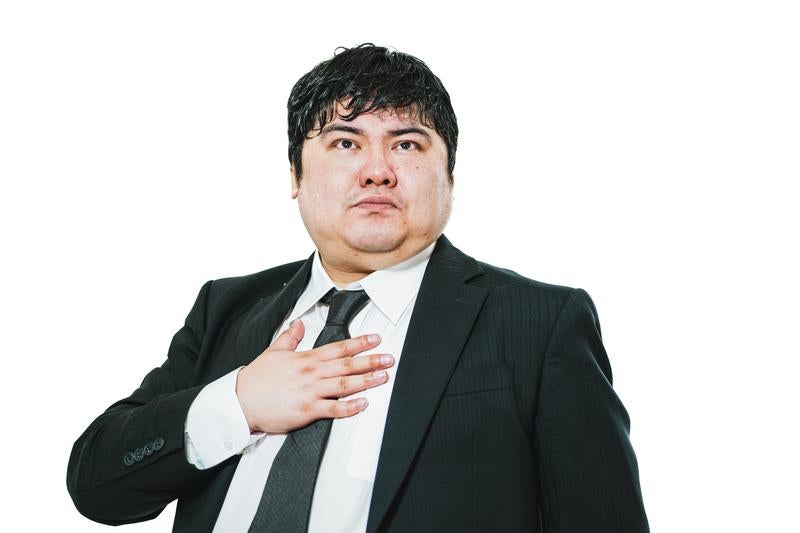 胸に手を当てて誓いを立てるスーツの男性の写真