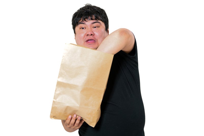 届いた小包の紙袋を開けて荷物の中身を探る男性の写真