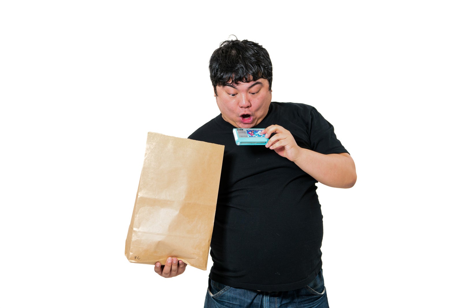 「レアなファミコンカセットを手に取り驚く男性」の写真［モデル：段田隼人］