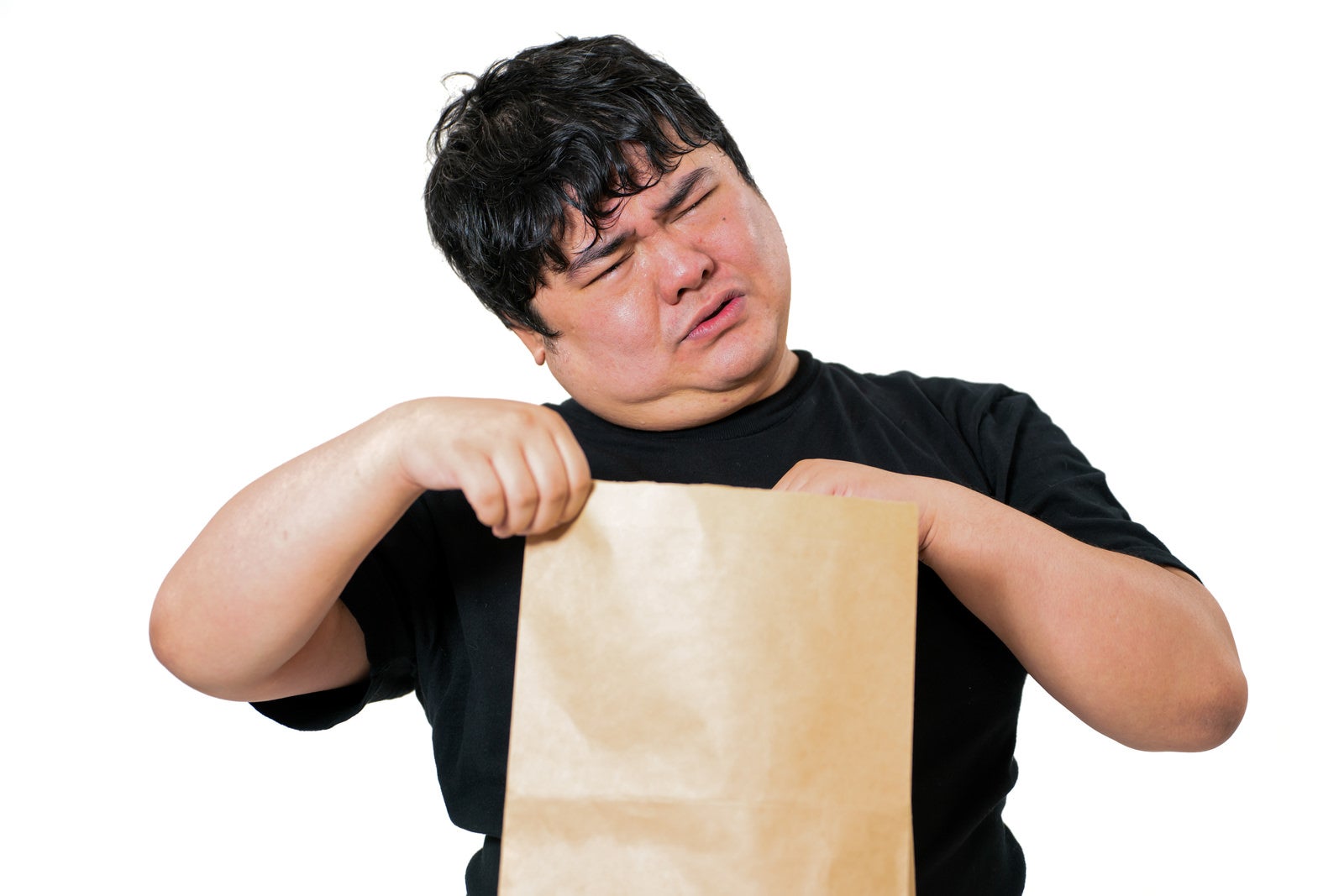 茶色い紙袋を両手で持ち、目をつむって確認する不安そうな表情の男性［モデル：段田隼人］