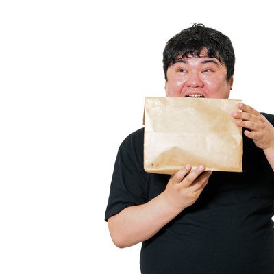 口を開けて紙包みを受け取る男性の驚き表情の写真
