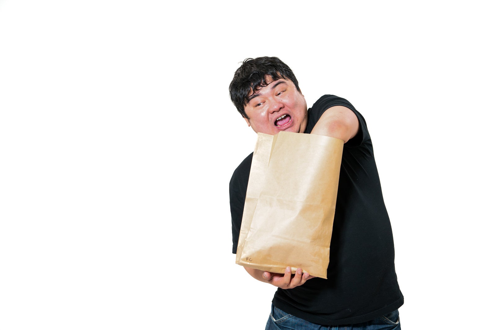 紙袋に両手を突っ込み開封する黒いTシャツの男性［モデル：段田隼人］