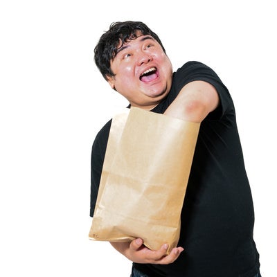 興奮して紙袋の中身に手を突っ込む男性の写真