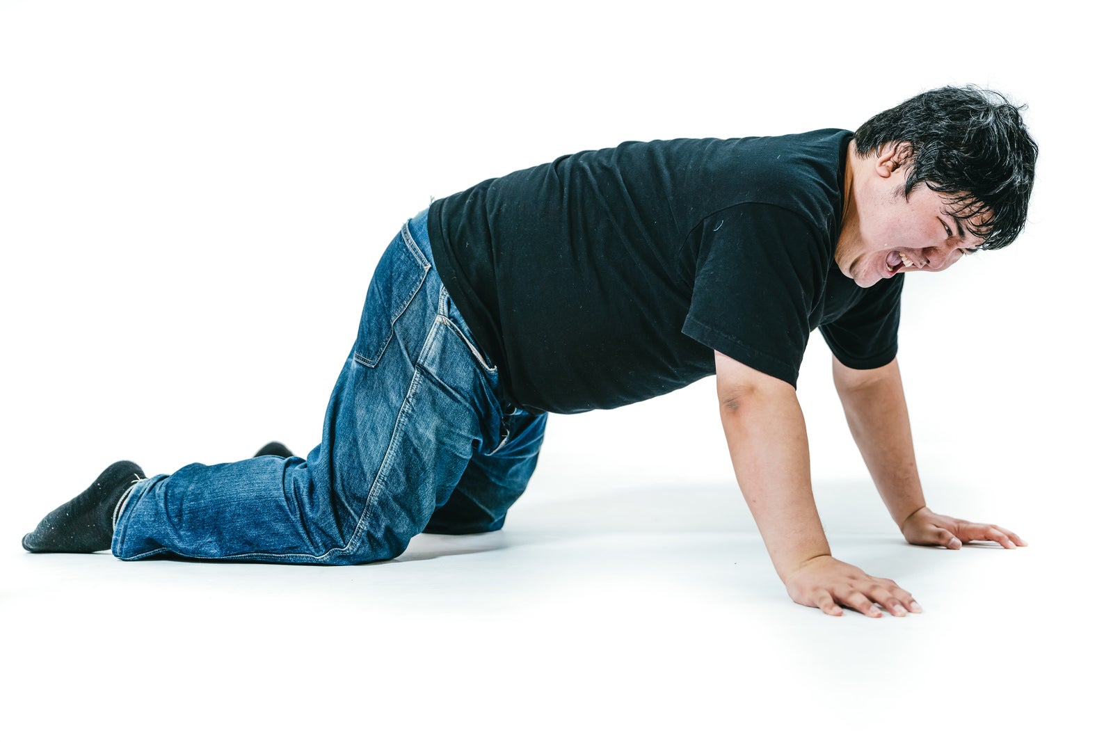 「膝をついて立ち上がろうとする男性」の写真［モデル：段田隼人］