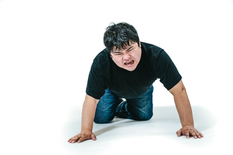 四つん這いで落ちた物を探す男性の写真