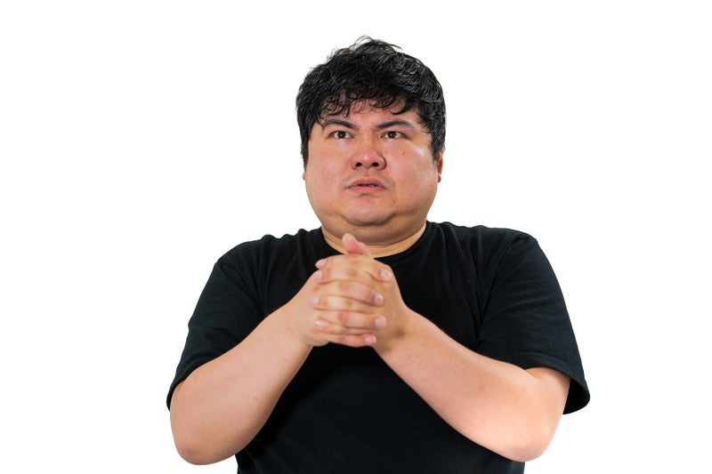 胸の前で手を握り真剣な表情を浮かべる男性の写真