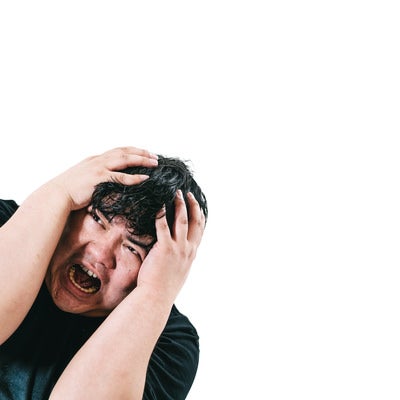 頭を抱えて悩み苦しむ男性の写真