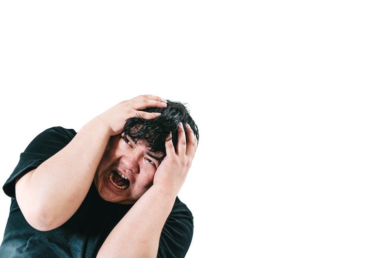 頭を抱えて悩み苦しむ男性の写真