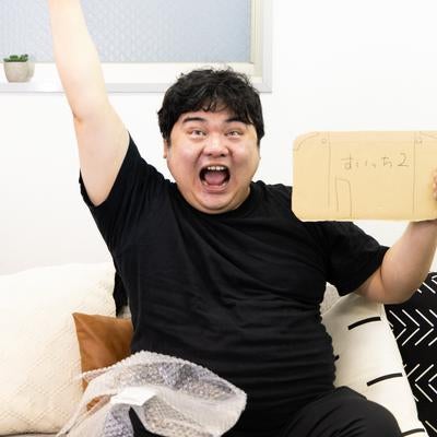 段ボール箱を掲げて喜ぶすいっち2をゲットした男性の写真