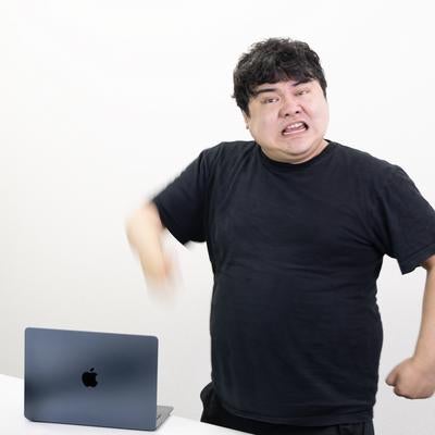 腕を振り下ろしてPCに怒りや苛立ちを叩く男性の写真