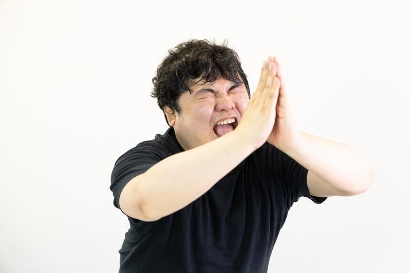 両手を合わせて懇願する男性の写真