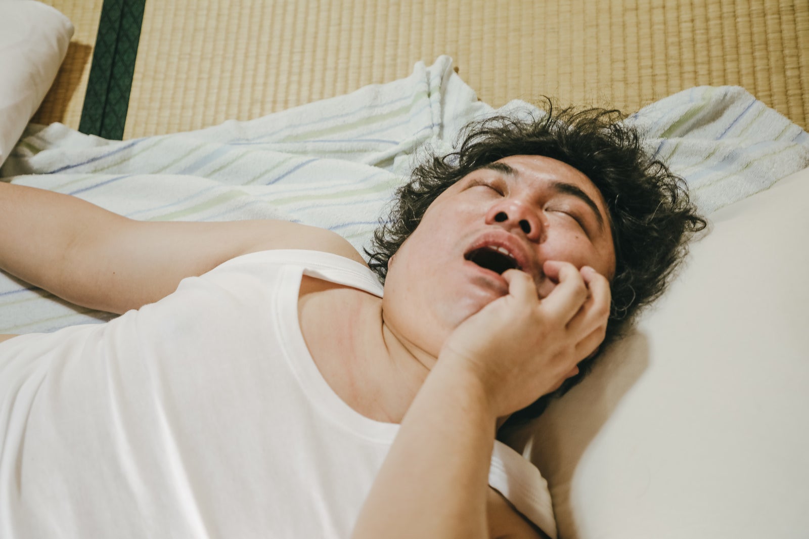 「寝ながら小指を食べる親父」の写真［モデル：段田隼人］