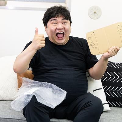 段ボール製ゲーム機を手に大喜びする男性の写真