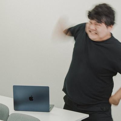 パソコンの前で怒りを爆発させる男性の写真