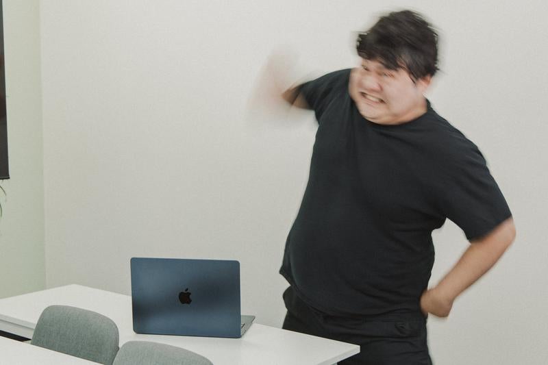 パソコンの前で怒りを爆発させる男性の写真