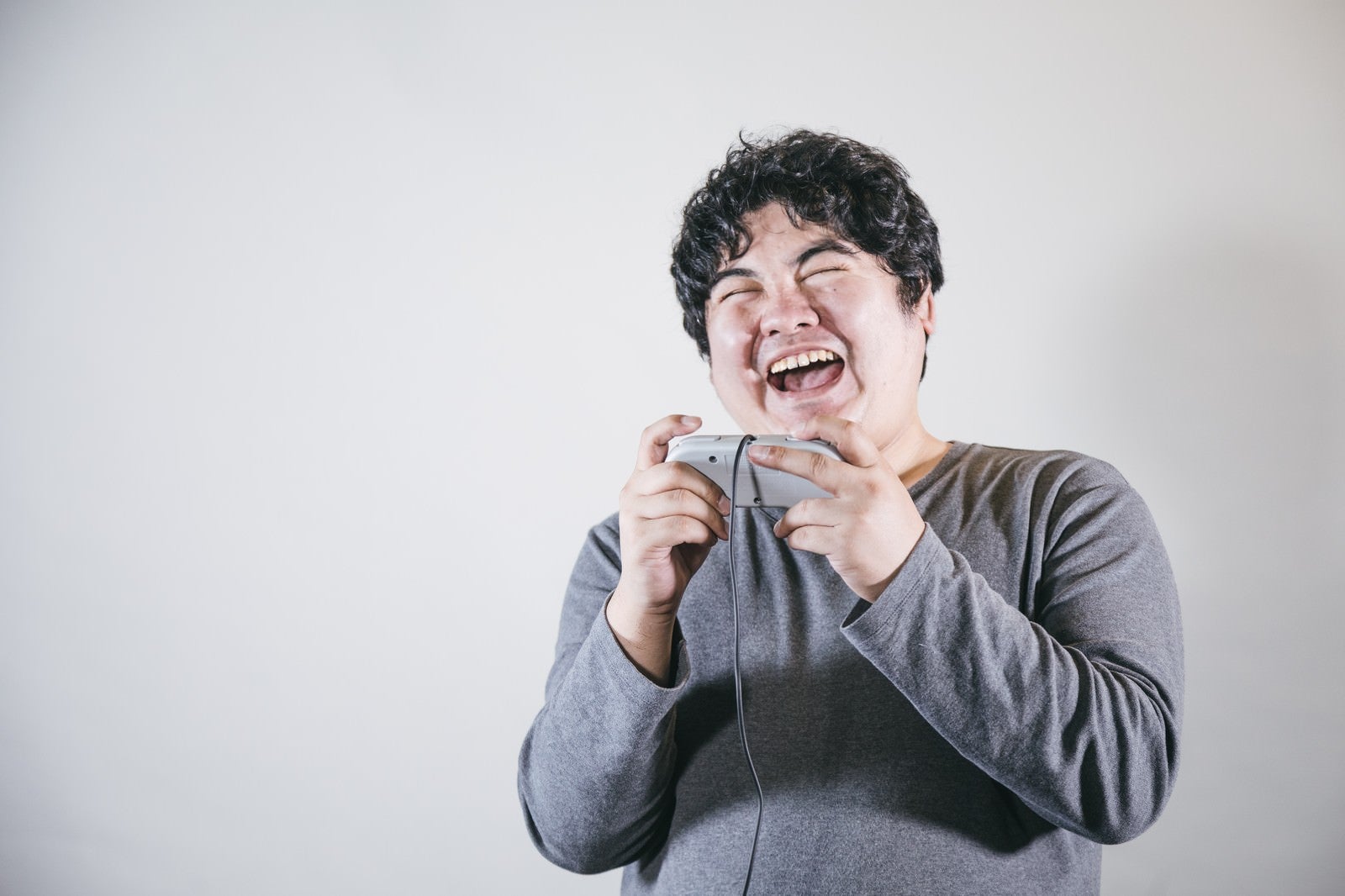 「ゲームをしながら爆笑する男性」の写真［モデル：段田隼人］