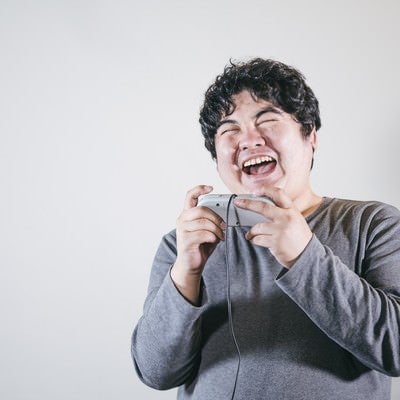 ゲームをしながら爆笑する男性の写真