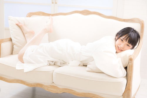 バスローブ姿でソファーに寝転ぶ若い女性の写真