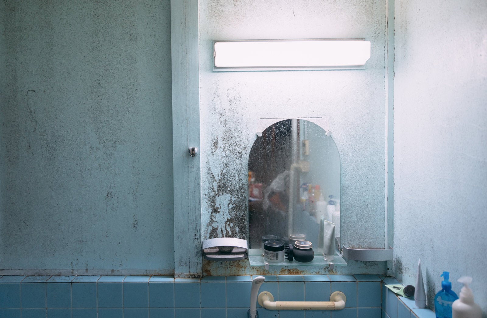 「壁のカビと薄汚れた風呂場の鏡」の写真